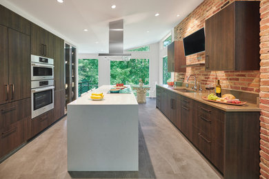 Mid-sized mid-century modern galley gray floor and vaulted ceiling eat-in kitchen photo in DC Metro with an undermount sink, flat-panel cabinets, dark wood cabinets, brick backsplash, stainless steel appliances and an island