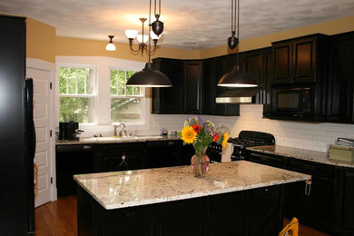 Eat-in kitchen - mid-sized traditional galley medium tone wood floor eat-in kitchen idea in Miami with a double-bowl sink, dark wood cabinets, marble countertops, white backsplash, ceramic backsplash, black appliances and an island