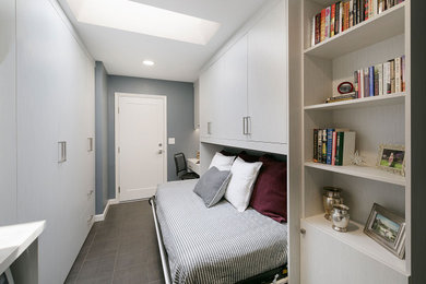 Small home studio in San Francisco with white walls, laminate floors, a built-in desk and grey floors.