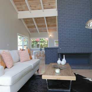 Bild på ett mellanstort funkis allrum med öppen planlösning, med ljust trägolv, en öppen hörnspis, en spiselkrans i tegelsten och vita väggar