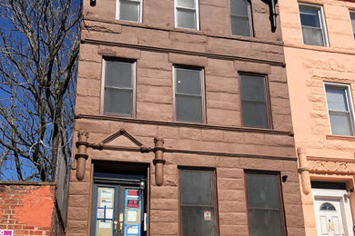 Ejemplo de fachada de piso marrón retro de tamaño medio con revestimiento de piedra y tejado plano