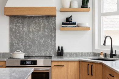 Mid-sized trendy u-shaped medium tone wood floor enclosed kitchen photo in Vancouver with an undermount sink, flat-panel cabinets, light wood cabinets, quartz countertops, stainless steel appliances, an island and gray countertops