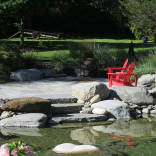 Photo of a mid-sized traditional backyard partial sun garden in Burlington with with pond and natural stone pavers.