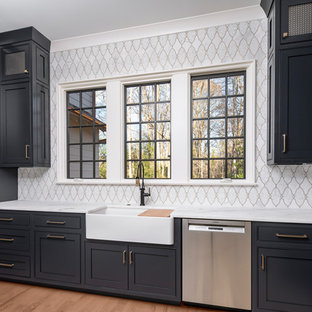 Mid-sized traditional kitchen pantry appliance - Example of a mid-sized classic l-shaped medium tone wood floor and brown floor kitchen pantry design in Charlotte with a farmhouse sink, blue cabinets, marble countertops, white backsplash, mosaic tile backsplash, stainless steel appliances and white countertops