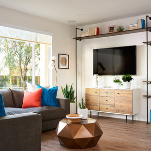 Example of a transitional medium tone wood floor family room design in Orange County with white walls and a wall-mounted tv