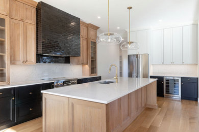 Example of a large cottage l-shaped light wood floor and brown floor eat-in kitchen design in Providence with an undermount sink, recessed-panel cabinets, light wood cabinets, quartz countertops, white backsplash, quartz backsplash, stainless steel appliances, an island and white countertops