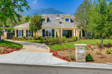 Inspiration for a large yellow two-story wood house exterior remodel in Los Angeles with a hip roof and a tile roof