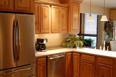 Inspiration for a mid-sized timeless l-shaped eat-in kitchen remodel in Wilmington with raised-panel cabinets, medium tone wood cabinets, laminate countertops, beige backsplash, stone slab backsplash, stainless steel appliances and a peninsula
