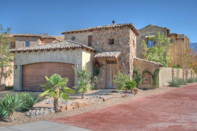 Mid-sized mediterranean beige two-story stone exterior home idea in Albuquerque with a hip roof
