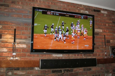 Mid-sized elegant family room photo in New York with brown walls, a standard fireplace, a brick fireplace and a wall-mounted tv