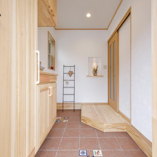 他の地域の地中海スタイルのおしゃれな玄関 (白い壁、茶色い床) の写真