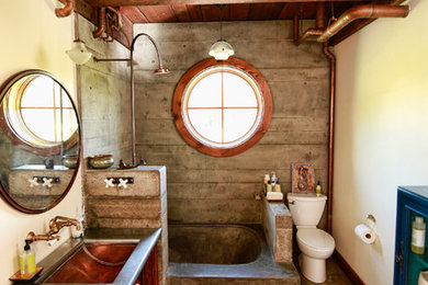 Bathroom - mid-sized industrial 3/4 porcelain tile concrete floor and brown floor bathroom idea in Other with open cabinets, medium tone wood cabinets, a two-piece toilet, yellow walls, an undermount sink, stainless steel countertops and gray countertops