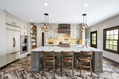 Inspiration for a large transitional l-shaped porcelain tile and multicolored floor kitchen remodel in Indianapolis with a farmhouse sink, beige cabinets, beige backsplash, travertine backsplash, paneled appliances, an island and white countertops