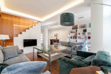 Inspiration for a mid-sized contemporary open concept living room in Seville with a library, white walls, dark hardwood floors, no fireplace and a freestanding tv.