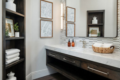 Example of a mid-sized transitional gray tile and marble tile medium tone wood floor, gray floor and single-sink alcove shower design in Phoenix with flat-panel cabinets, dark wood cabinets, a one-piece toilet, gray walls, an undermount sink, marble countertops, a hinged shower door, white countertops and a floating vanity
