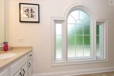 Bathroom - large beige tile and marble tile marble floor, beige floor, single-sink and vaulted ceiling bathroom idea in New York with white cabinets, a two-piece toilet, beige walls, an undermount sink, quartz countertops, beige countertops and a built-in vanity