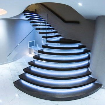 Illuminated floating staircase with huge curved treads