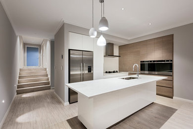 Photo of a modern kitchen in Perth with an undermount sink, white cabinets, solid surface benchtops, white splashback, stone slab splashback, stainless steel appliances, vinyl floors, with island, grey floor and white benchtop.