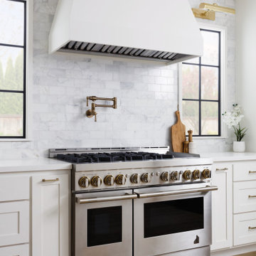 Bright white kitchen with large hood and pot filler
