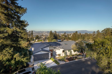 Large trendy white two-story stucco exterior home photo in San Francisco with a metal roof and a gray roof