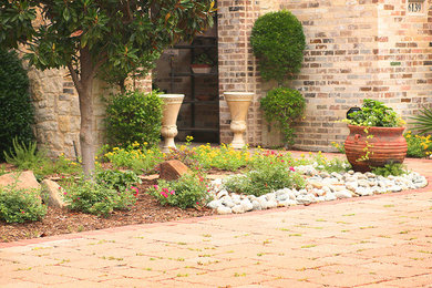 This is an example of a mid-sized traditional front yard full sun xeriscape for summer in Dallas with brick pavers.