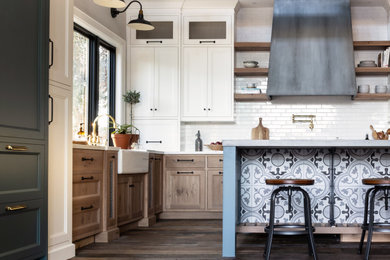 Example of a large country l-shaped medium tone wood floor, brown floor and vaulted ceiling open concept kitchen design in San Francisco with a farmhouse sink, shaker cabinets, blue cabinets, concrete countertops, white backsplash, porcelain backsplash, paneled appliances, an island and gray countertops