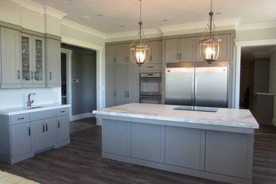 Inspiration for a large u-shaped enclosed kitchen remodel in Toronto with an undermount sink, flat-panel cabinets, gray cabinets, solid surface countertops, stainless steel appliances and an island