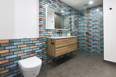 Photo of a mid-sized eclectic 3/4 bathroom in Melbourne with flat-panel cabinets, brown cabinets, an open shower, a wall-mount toilet, multi-coloured tile, ceramic tile, multi-coloured walls, ceramic floors, an integrated sink, engineered quartz benchtops, grey floor, an open shower, white benchtops, a single vanity and a floating vanity.