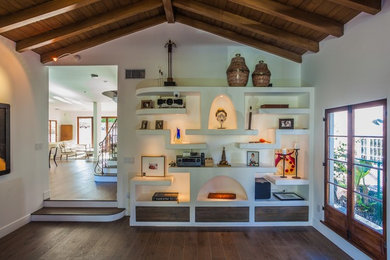 Mid-sized tuscan enclosed dark wood floor and brown floor family room photo in Los Angeles with white walls, a standard fireplace, a plaster fireplace and no tv