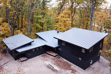 Contemporary black wood exterior home idea in Other with a mixed material roof