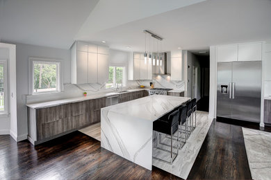 Mid-sized minimalist l-shaped porcelain tile and white floor eat-in kitchen photo in Providence with an undermount sink, flat-panel cabinets, white cabinets, quartz countertops, white backsplash, stone slab backsplash, stainless steel appliances, an island and white countertops
