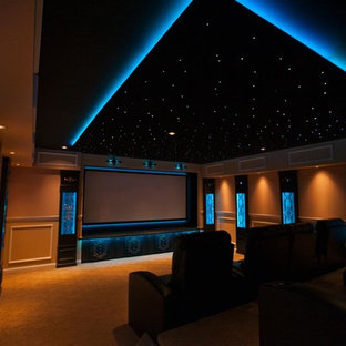 Inspiration pour une grande salle de cinéma traditionnelle fermée avec un mur beige, moquette, un écran de projection et un sol orange.