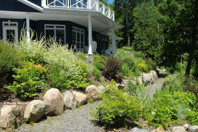 Photo of a large modern sloped full sun xeriscape in Toronto with a retaining wall and gravel.