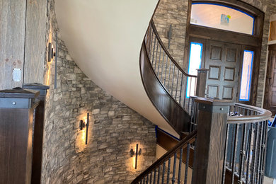 他の地域にある高級な広いトラディショナルスタイルのおしゃれなスケルトン階段 (木の蹴込み板、混合材の手すり、レンガ壁) の写真