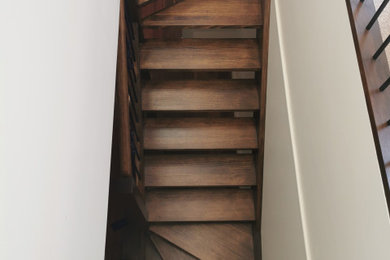 Ejemplo de escalera en L tradicional con escalones de madera y contrahuellas de madera