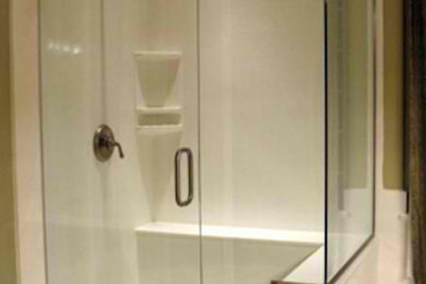 Example of a medium tone wood floor corner shower design in Phoenix with green walls