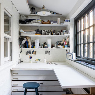 Ejemplo de sala de manualidades industrial, pequeña, sin chimenea, con paredes blancas, suelo de piedra caliza, escritorio empotrado y suelo gris