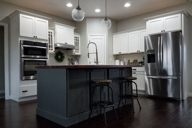 Inspiration for a large transitional l-shaped medium tone wood floor and brown floor kitchen remodel in Chicago with shaker cabinets, stainless steel appliances and an island