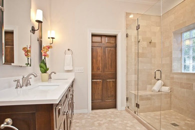 Example of a large transitional master ceramic tile and beige floor alcove shower design in Other with recessed-panel cabinets, brown cabinets, a one-piece toilet, white walls, an undermount sink, quartzite countertops and a hinged shower door
