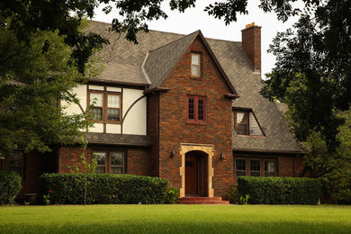 This is an example of a large traditional three-storey brick brown house exterior in Wichita with a gable roof and a shingle roof.