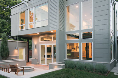 Example of a mid-sized trendy gray two-story stucco gable roof design