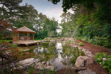 Photo of a large rustic partial sun backyard water fountain landscape in Toronto with decking for summer.