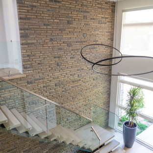 Große Moderne Holztreppe in L-Form mit offenen Setzstufen, Glasgeländer und Ziegelwänden in Toronto