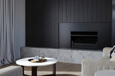 Mid-sized modern formal open concept living room in Auckland with black walls, medium hardwood floors, a standard fireplace, a metal fireplace surround, a concealed tv, brown floor and planked wall panelling.