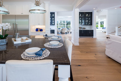 Eat-in kitchen - mid-sized traditional medium tone wood floor eat-in kitchen idea in Los Angeles with an undermount sink, flat-panel cabinets, white cabinets, granite countertops, white backsplash, subway tile backsplash, stainless steel appliances and an island