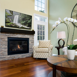 Immagine di un piccolo soggiorno tradizionale aperto con sala giochi, pareti verdi, pavimento in legno massello medio, camino classico, cornice del camino in pietra e TV a parete