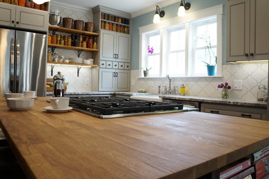 This is an example of a mid-sized country l-shaped eat-in kitchen in Denver with a farmhouse sink, beaded inset cabinets, grey cabinets, wood benchtops, white splashback, porcelain splashback, stainless steel appliances and with island.