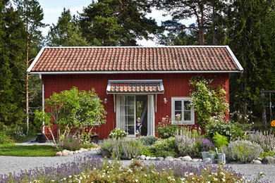 Design ideas for a mid-sized country one-storey red exterior in Stockholm with wood siding and a gable roof.