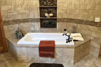Inspiration for a large modern master beige tile, brown tile and porcelain tile porcelain tile drop-in bathtub remodel in Other with raised-panel cabinets, dark wood cabinets, beige walls, an undermount sink and granite countertops