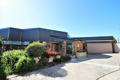 Inspiration for a large industrial split-level brick brown house exterior in Sydney with a shed roof and a metal roof.